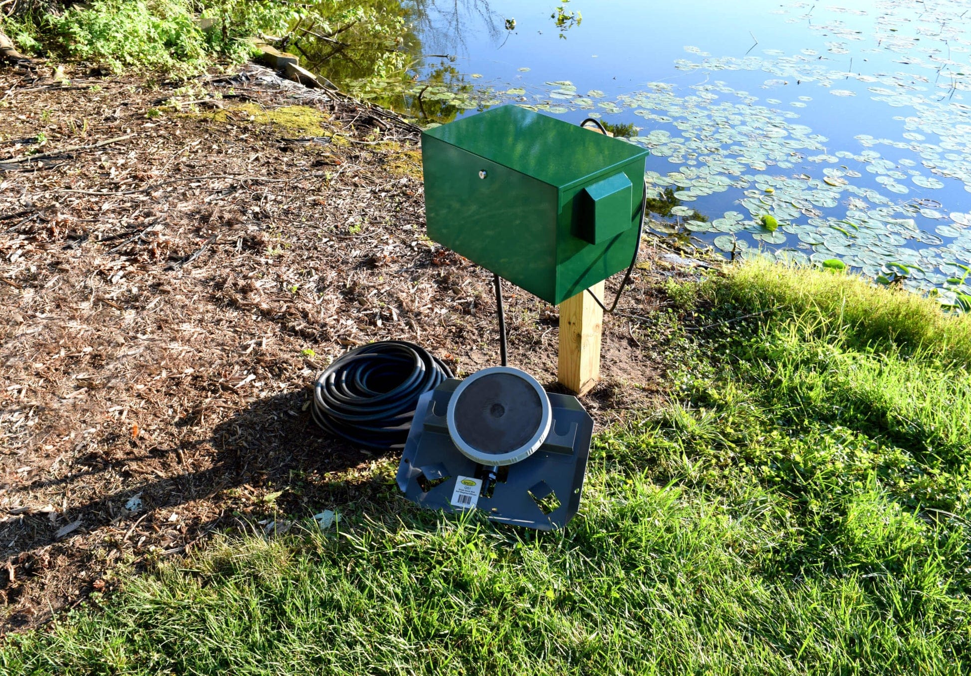 Pond aerator for 1 acre with compressor and hose setup beside a pond for effective oxygenation.