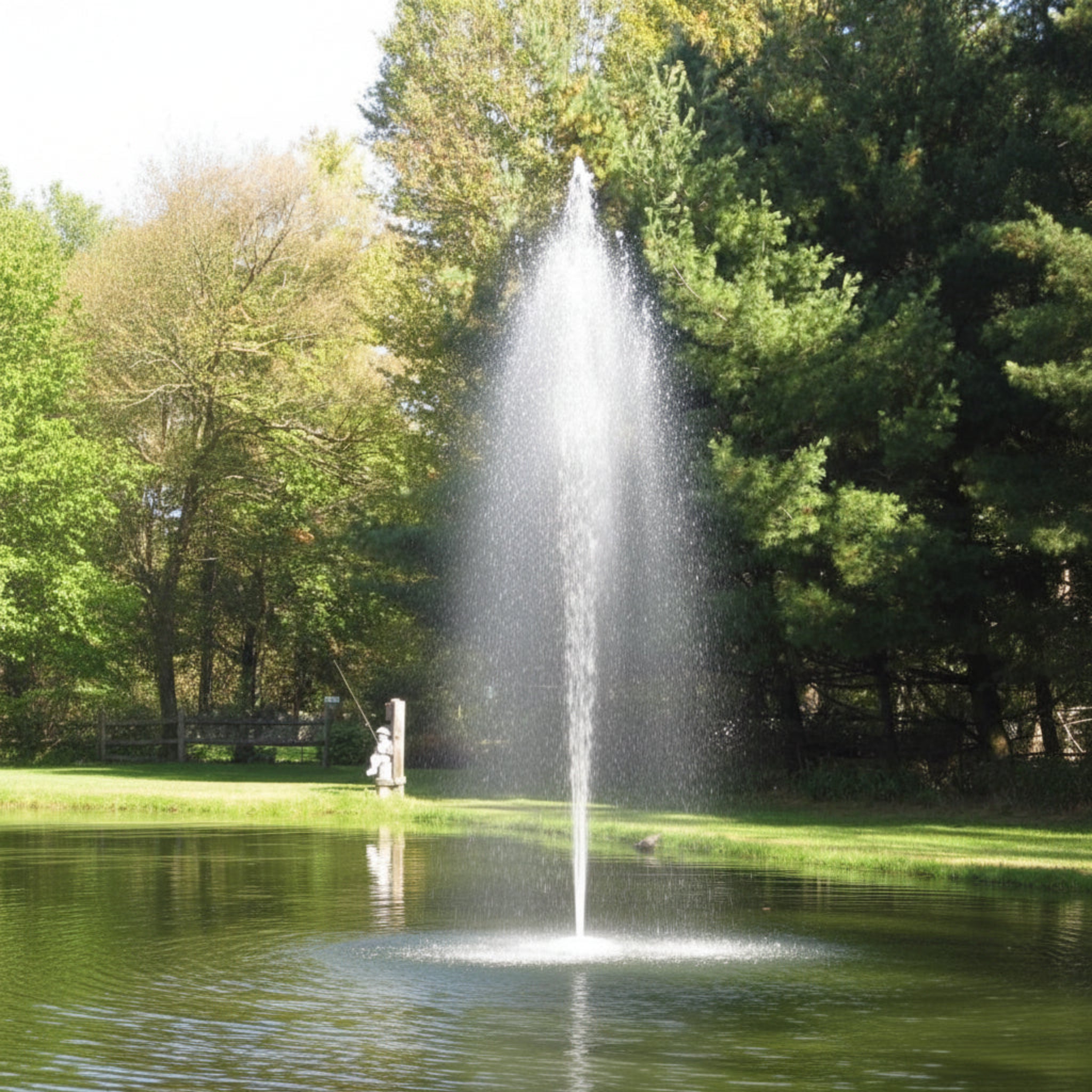 Floating fountain nozzle spraying water into a tranquil pond surrounded by trees.